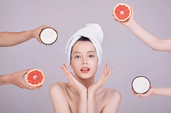 Cute girl chooses between coconut and grapefruit. — Stock Photo, Image