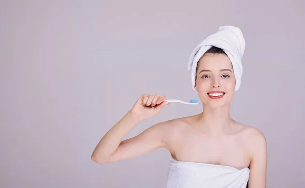 Усміхнена дівчина в рушнику з зубною щіткою в руці . — стокове фото