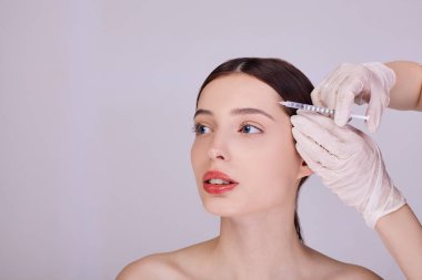Doktor genç bir kızın alnına iğne yapıyor..