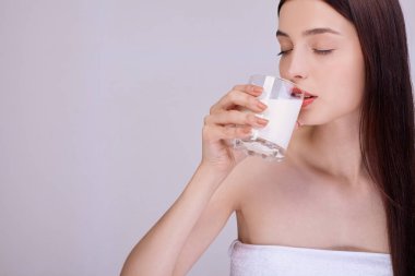 Havlulu bir kız gözleri kapalı süt içer..