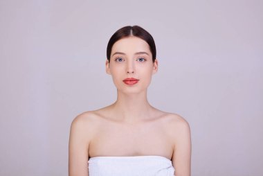 Beyaz havluyla genç bir kız çerçevenin içine bakar..