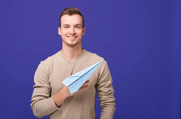 A handsome guy with a smile holds a paper plane. — Stock Photo, Image