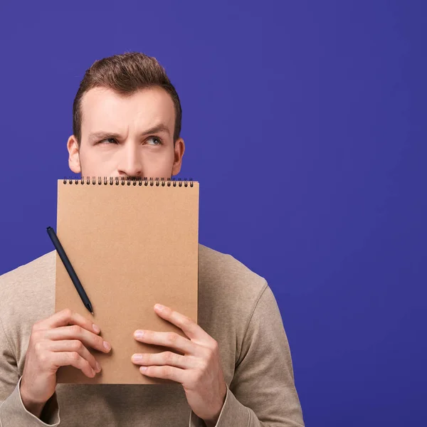 Handsome man holds a brown notebook. — Stock Photo, Image
