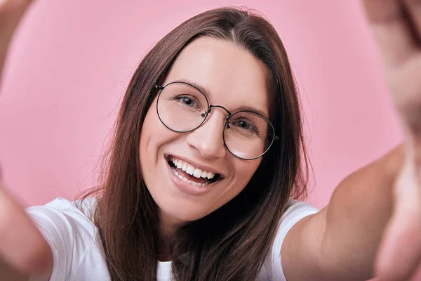 Cute happy girl in glasses smiling broadly and takes a selfie — Stock Photo, Image
