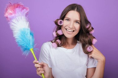 Pembe bukleli neşeli ev hanımı bir pidasterle toz alır..