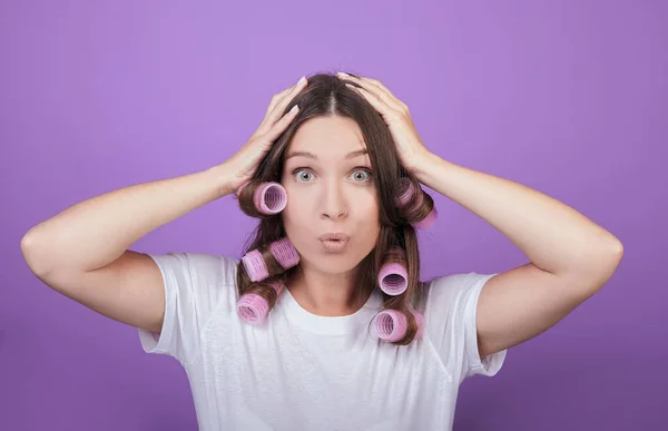 Funny girl with curlers clings to her head. — Stock Photo, Image