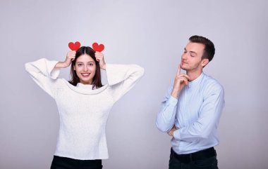 Güzellik uzmanı, iki kırmızı karton kalbi hayvan kulağı gibi kafasında tutan kıza bakıyor.