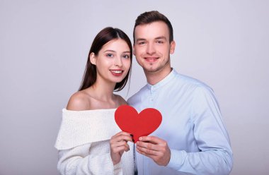Mutlu çift ellerinde kırmızı bir kalp ve gülümsüyor..