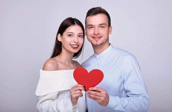 Casal feliz segurando um coração vermelho e sorrindo . — Fotografia de Stock