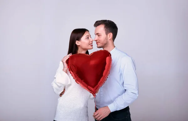 Elegante pareja sobre un fondo gris con un corazón rojo . — Foto de Stock