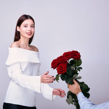 Kibar bir gülümsemesi olan genç bir kız kırmızı güller alır..