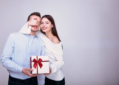 Genç bir kız bir erkeğe hediye verir ve gözlerini kapatır..