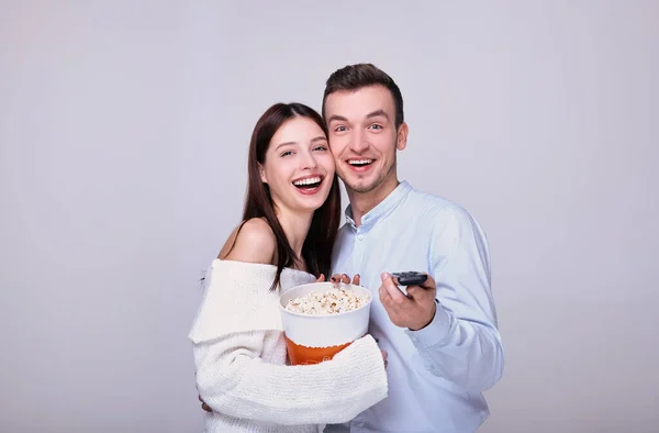 Um cara e uma garota com um controle remoto de TV comem pipocas . — Fotografia de Stock