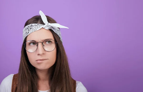 Das Mädchen mit der runden Brille beißt sich auf die Lippe und schaut weg. — Stockfoto