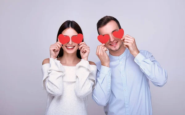 Щаслива молода пара тримає червоні паперові серця і посміхається . — стокове фото