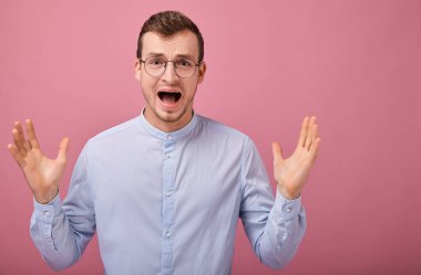Adam kollarını yanlara açtı. Gökyüzü mavisi gömlekli ve bilgisayar gözlüklü havalı bir adam pembe arka planda duruyor. Girişimci, yılın çalışanı. İş adamı bağırıyor..