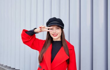 Sevimli gülümseyen güzel, gözünün yanında bir barış işareti tutuyor.