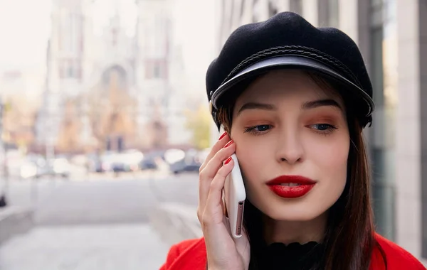 A calm unforgettable stranger in a dark kepi talks on mobile phone and looks down — 图库照片