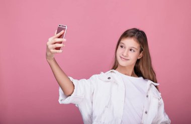 Kız pembe arka planda dururken selfie çekiyor..