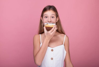 Şaşırmış bir kız beyaz jöleli çörek yiyor..