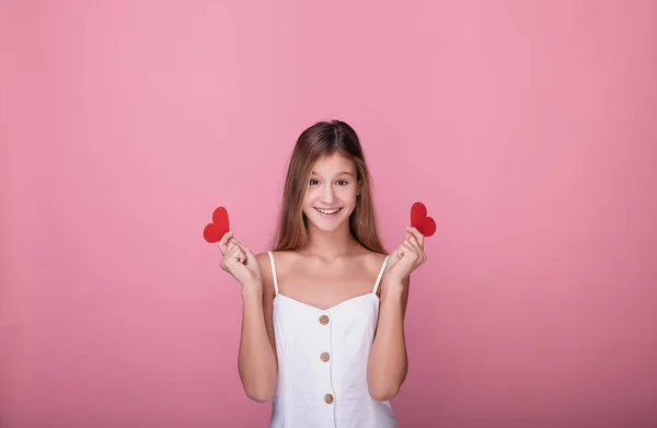 Χαριτωμένο κορίτσι με χάρτινες κόκκινες καρδιές σε ροζ φόντο. — Φωτογραφία Αρχείου