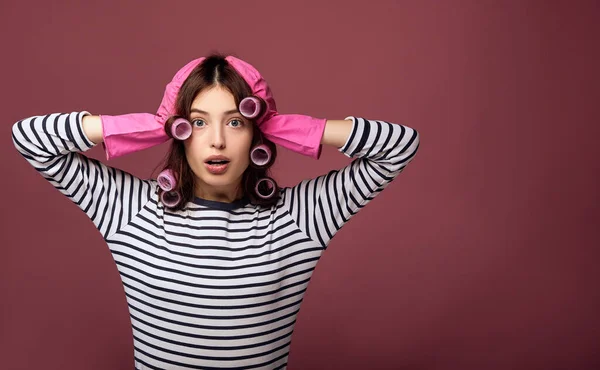 A frightened girl in curlers and rubber gloves clutched her head in her hands. — ストック写真