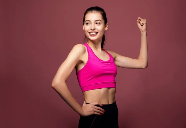 Portret van een vrolijke fitnessvrouw die biceps buigt. — Stockfoto