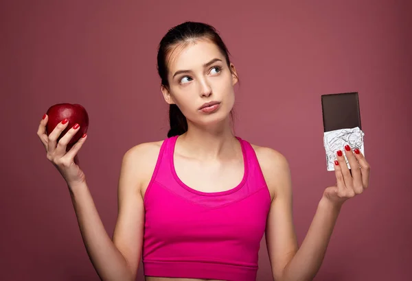 Fitness lady with red apple and chocolate bar. — ストック写真