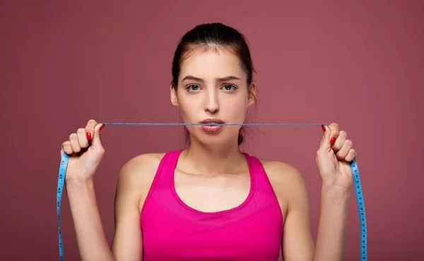 Chica deportiva con una cinta métrica sobre un fondo rosa . — Foto de Stock