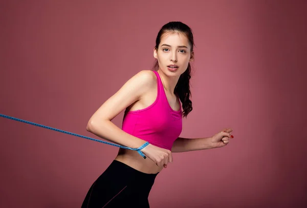 Menina encantadora em sportswear segurando fita métrica . — Fotografia de Stock