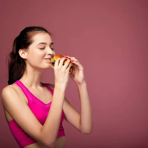 Caucasian girl eats hamburger with pleasure. — Stock Photo, Image