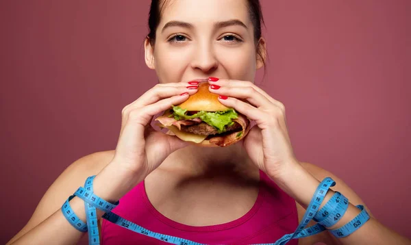 Chica blanca en una dieta felizmente come una hamburguesa grande con queso . — Foto de Stock