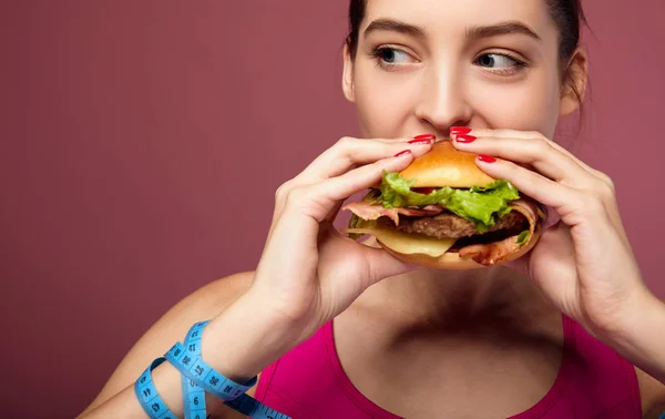 Lovely diet girl enjoys eating a big cheeseburger with pleasure. — Stock Photo, Image