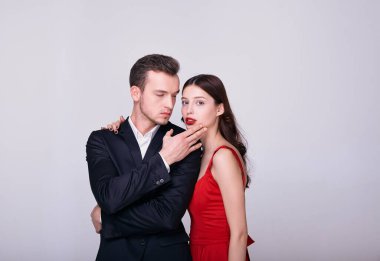 Beyaz bir arka planda seksi bir esmerle takım elbiseli vahşi bir adam..