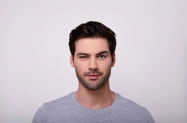 Kamera gri arka plan karşı dururken bakarak yakışıklı genç.