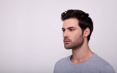 Siyah saçlı, kendine güvenen bir adam başka tarafa bakıyor..