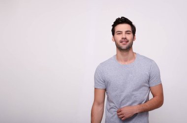 Kameraya bakıp tişörtünü ayarlayan, beyaz arka planda duran yakışıklı bir adam..