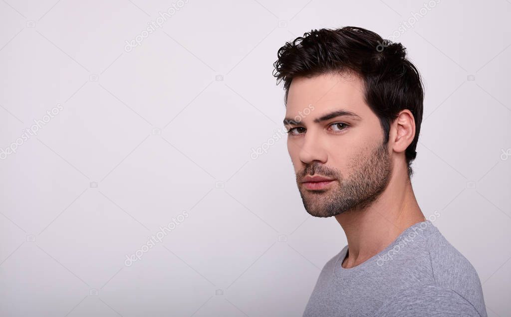 Cute young man in a gray T-shirt on a white background.