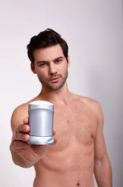 Вертикальная съемка крутого голого парня с дезодорантом в правой руке — стоковое фото