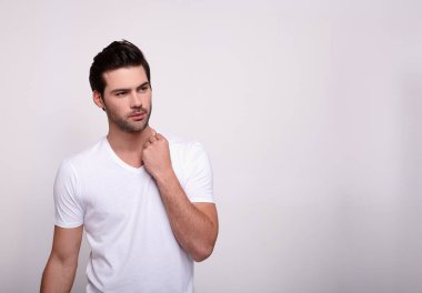 Genç ve yakışıklı esmer bir adam beyaz bir arka planda poz veriyor..