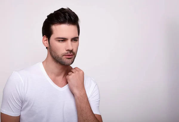 Beyaz arka planda beyaz tişörtlü çekici bir genç..