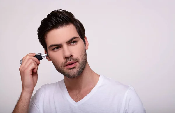 Um cara branco jovem remove o cabelo em seu sono ealone . — Fotografia de Stock