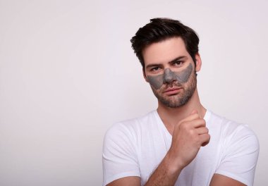 Beyaz bir arka planda, killi maskeli, sakin, yakışıklı bir adam..