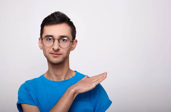 Snygg ung man med glasögon och en blå T-shirt på en vit bakgrund. — Stockfoto