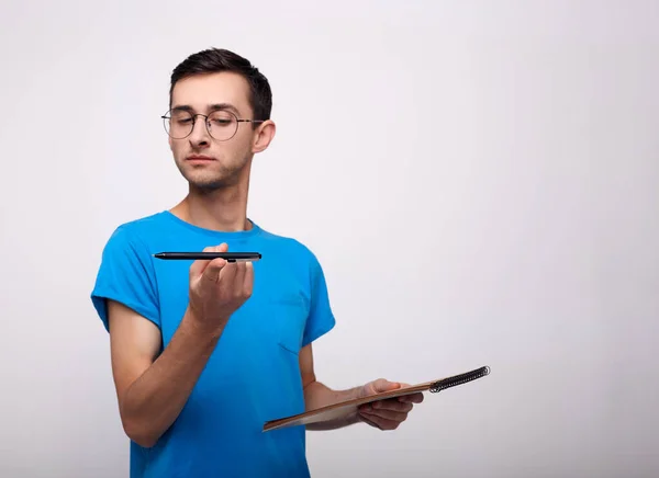 Um jovem moreno com óculos com uma caneta sobre um fundo branco . — Fotografia de Stock