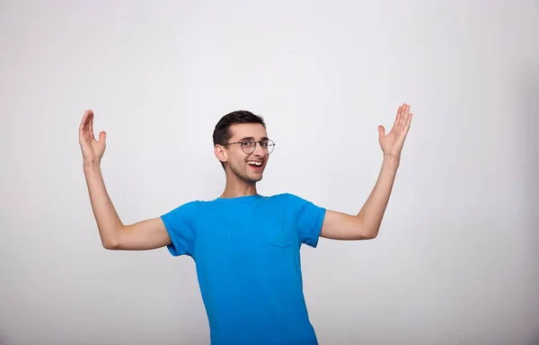 Jovem alegre surpreso em uma camiseta azul em um fundo branco . — Fotografia de Stock