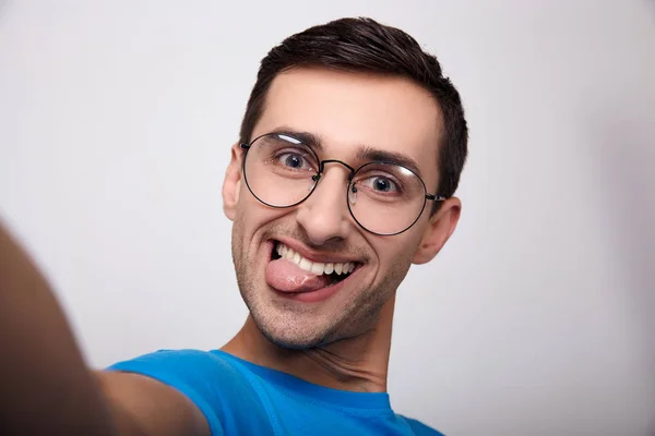 Um grande plano retrato de um jovem com óculos com a língua presa para fora . — Fotografia de Stock