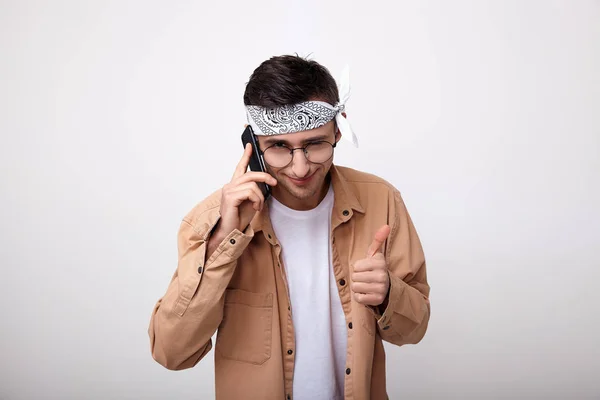 Um jovem alegre fala ao telefone e mostra à mão um sinal de como . — Fotografia de Stock