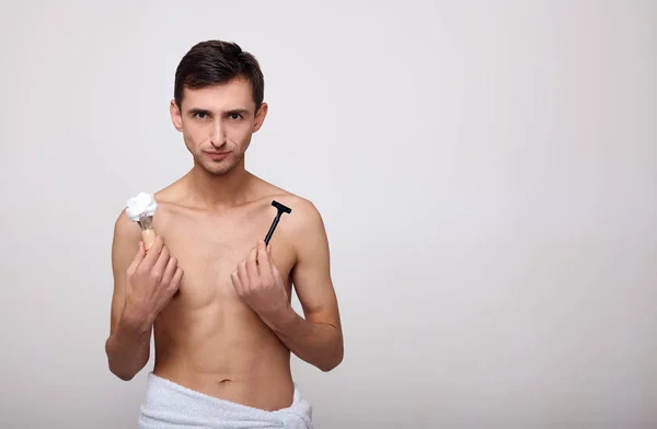 Guapo feliz hombre con espuma de afeitar celebración de la máquina de afeitar . — Foto de Stock