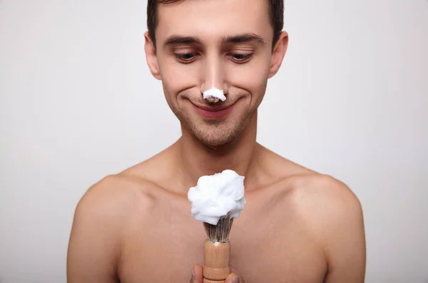 Detailní záběr je legrační chlap s pěnou na holení na nose a holení šmouha v ruce. — Stock fotografie